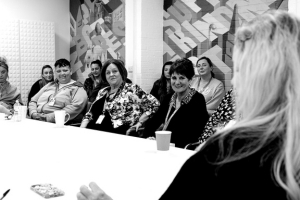 Group of social care workers chatting and smiling around a table during a meeting